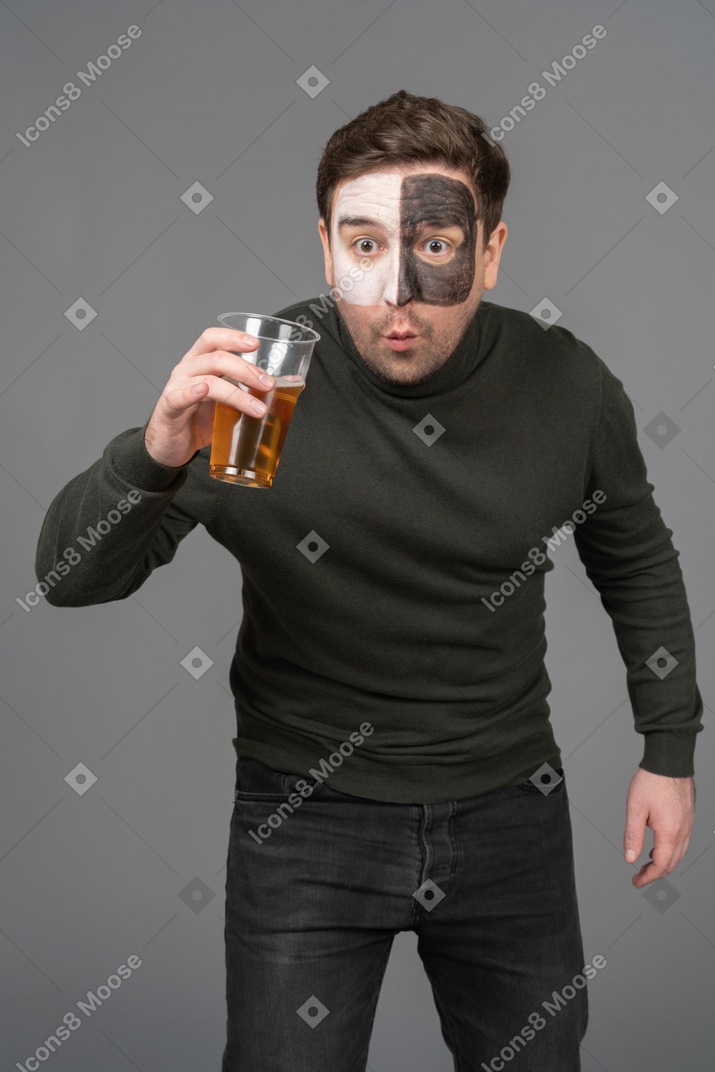 Front view of a surprised male football fan holding a beer