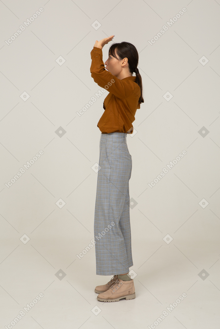 Vue latérale d'une jeune femme asiatique en culotte et chemisier levant les mains