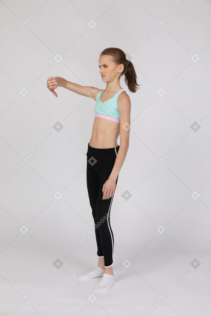 Disappointed teen girl in sportswear showing thumb down
