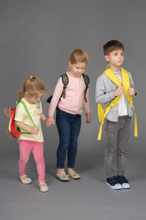 Tres niños con mochilas volviendo a la escuela.