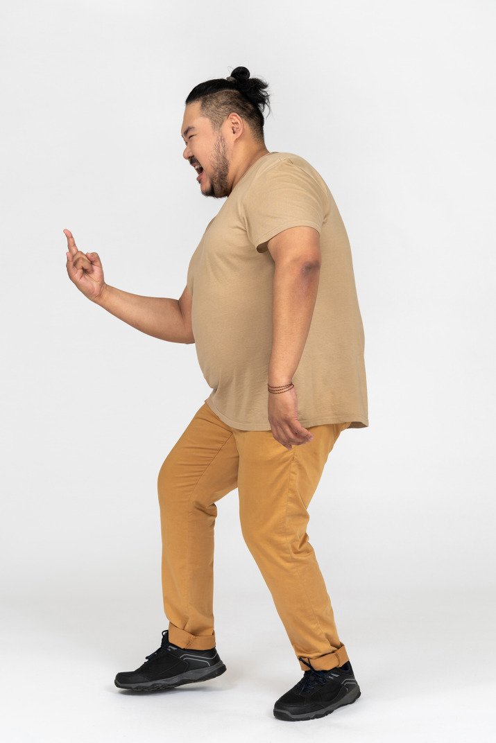 Excited plus size asian man making rock gesture in profile