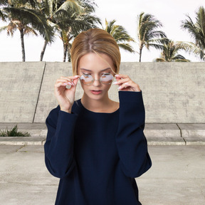 A woman in a blue sweater is adjusting glasses