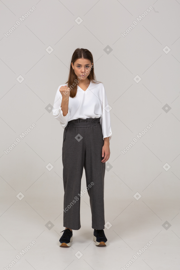 一位愤怒的年轻女士在办公室服装紧握拳头的前视图