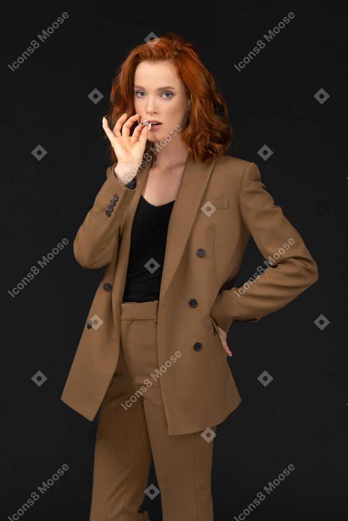 Front view of a young businesswoman posing with cigarette