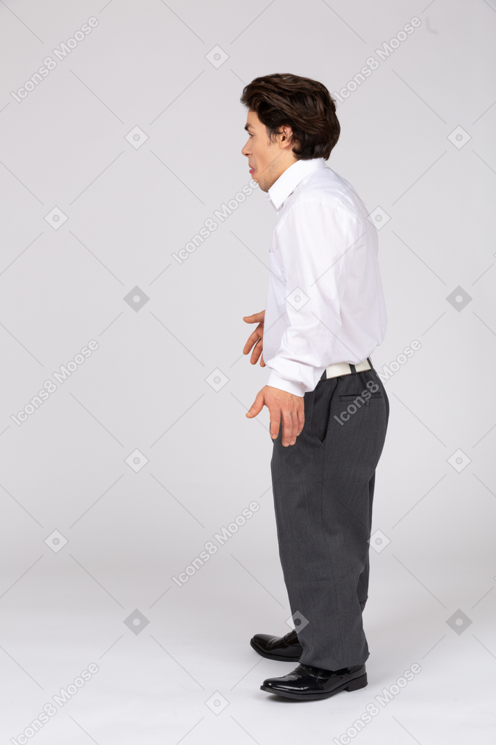 Vista lateral de um jovem em roupas casuais de negócios, mostrando a língua