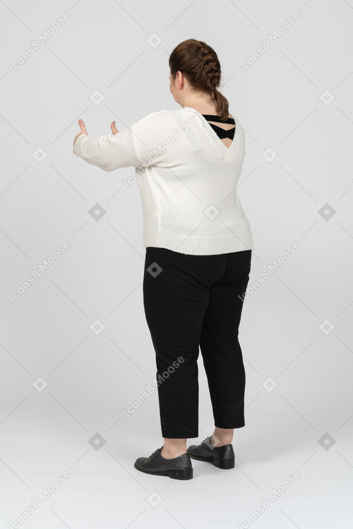 Mulher rechonchuda em roupas casuais mostrando os polegares para cima