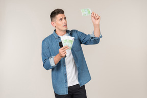 Young stand-up comic looking carefully at banknotes he's holding