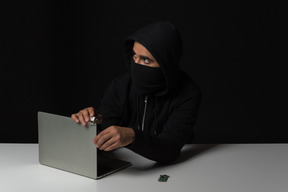 Cara hacker removendo laptop no escuro