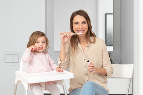 Young woman and her daughter brushing teeth together