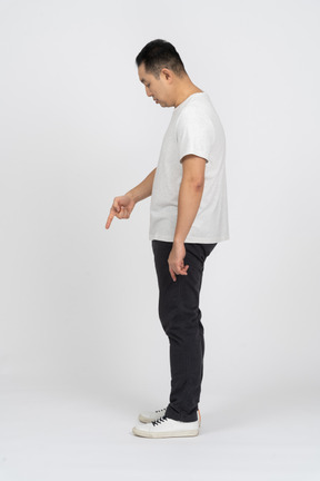 Side view of a man in casual clothes pointing down