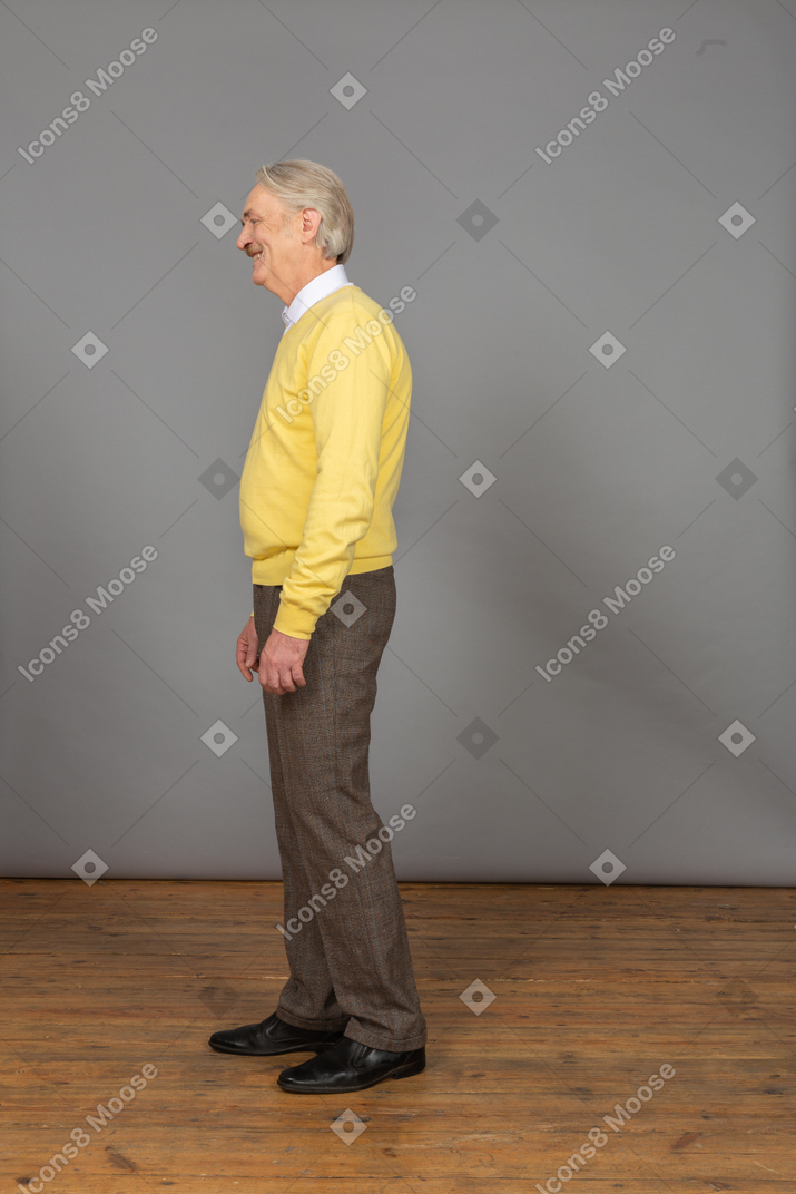 Ansicht eines lachenden alten mannes, der gelben pullover trägt und beiseite schaut