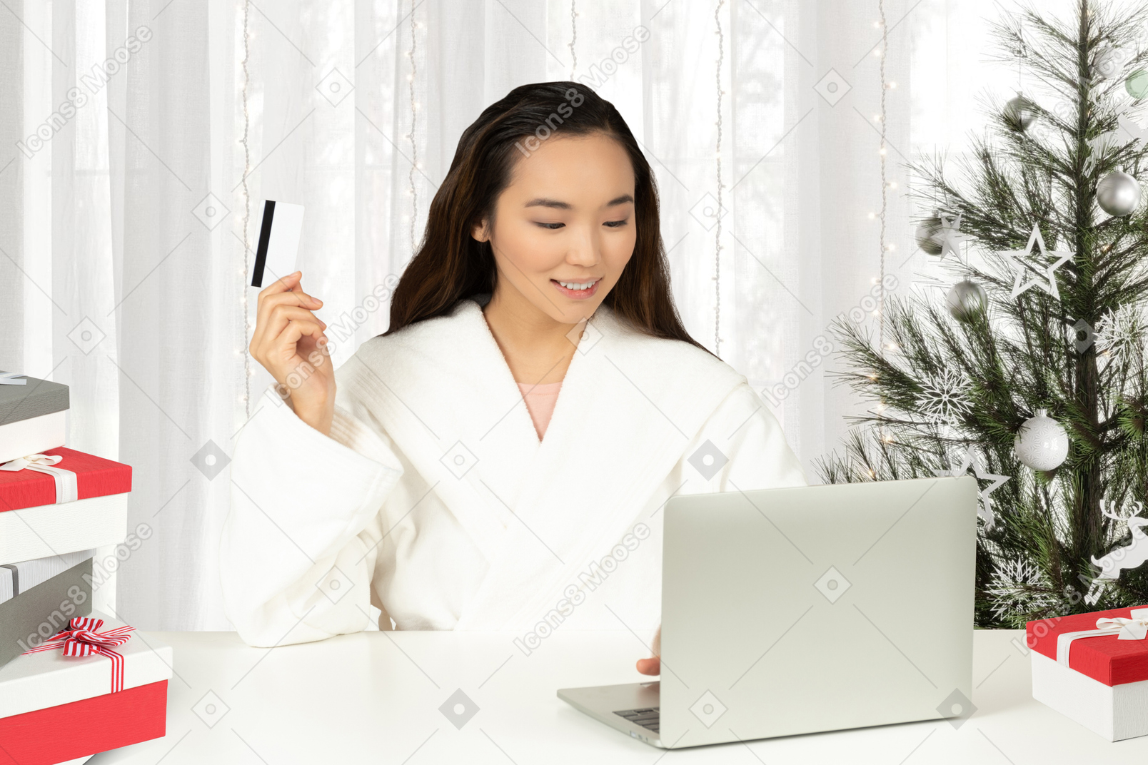 Young asian woman sitting at her laptop near a christmas tree