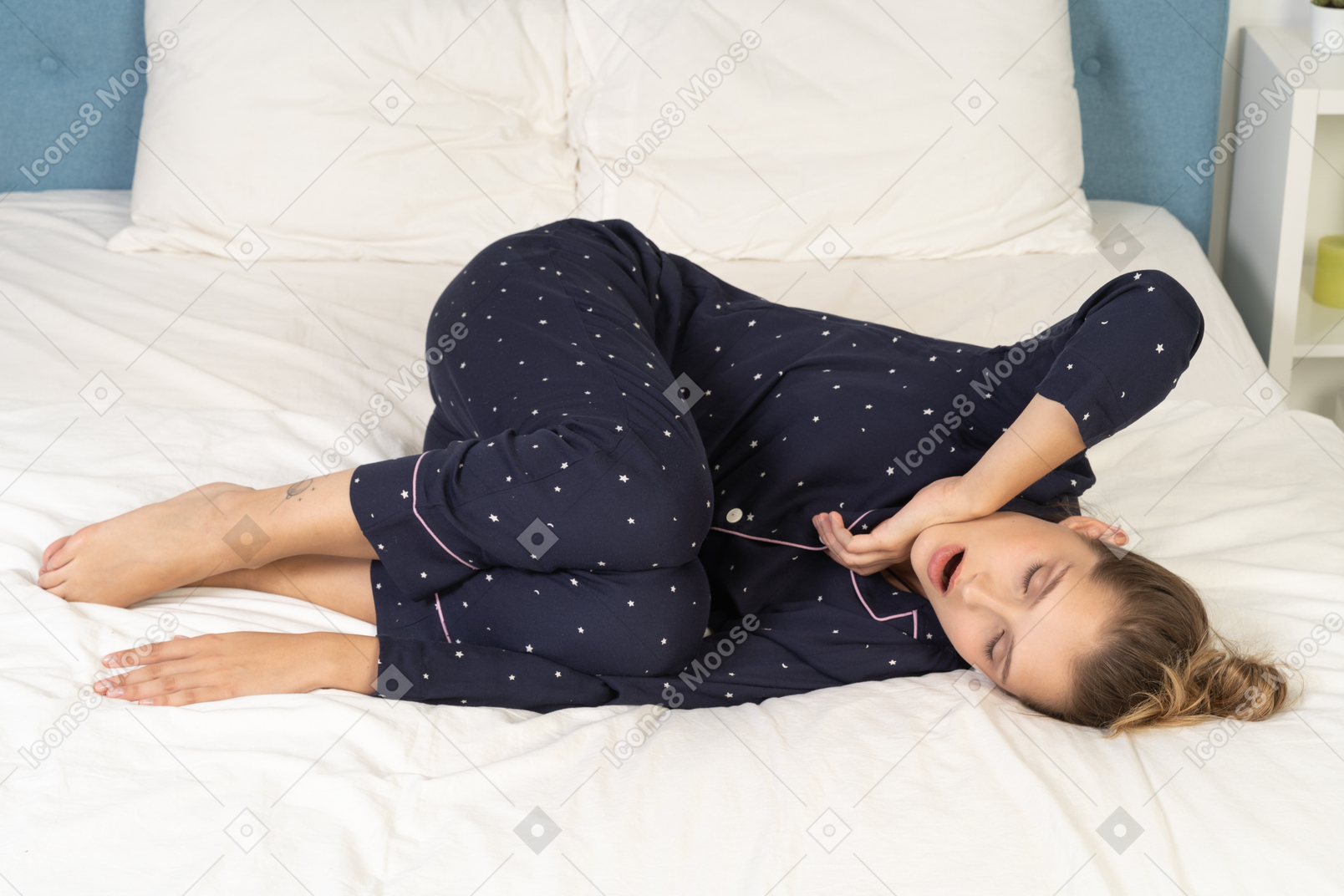 Full-length of a yawning young lady in pajamas laying in bed