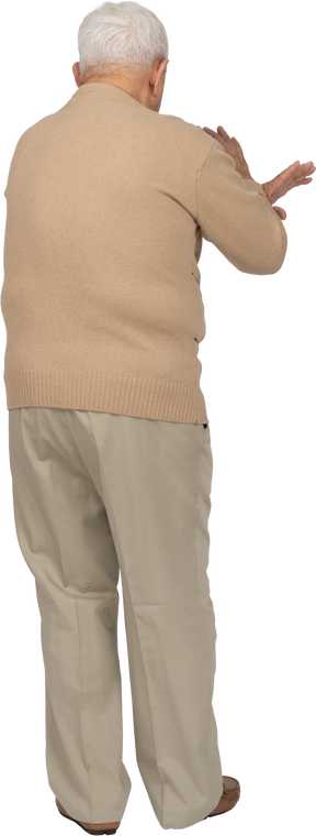 Rear view of an old man in casual clothes showing stop gesture