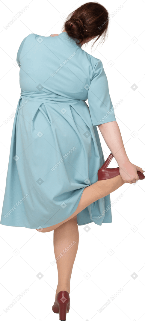 一个穿着蓝色连衣裙的女人在一条腿上保持平衡的后视图