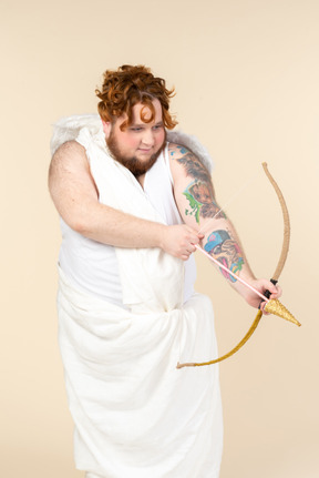 Young big man dressed as a cupid pointing with an arrow