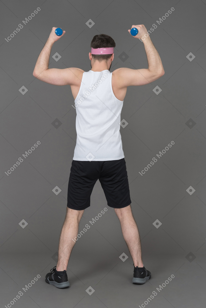 Homem desportivo com uma construção muscular levantando halteres