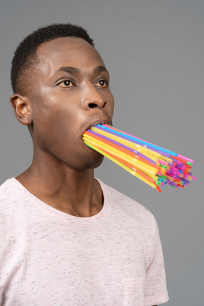 Jeune homme avec un tas de pailles dans la bouche