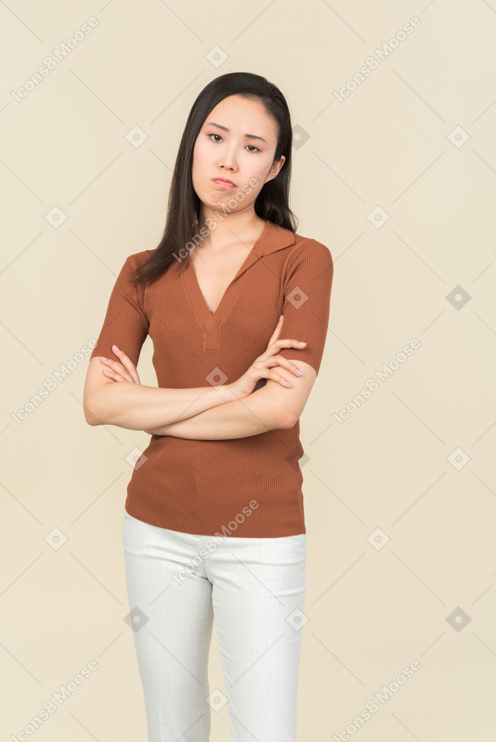 Doubtful young woman standing with hands crossed