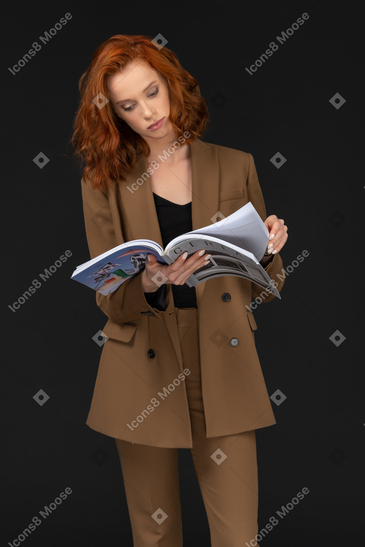 Vorderansicht einer jungen geschäftsfrau, die eine zeitschrift liest