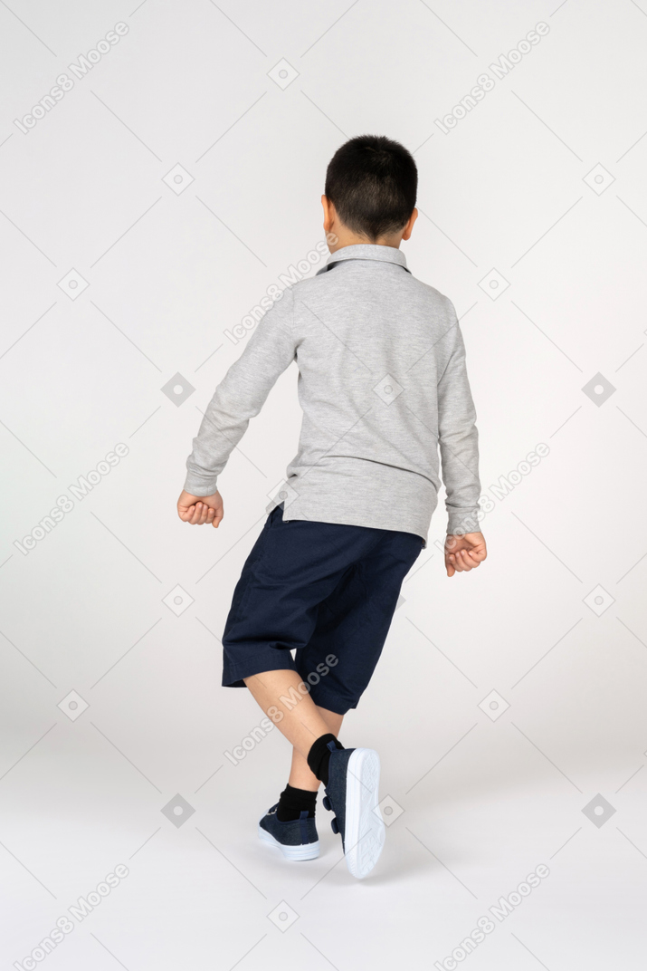 走っている小さな男の子の背面図