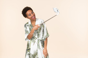 Laughing adult afro woman making a selfie with selfie stick