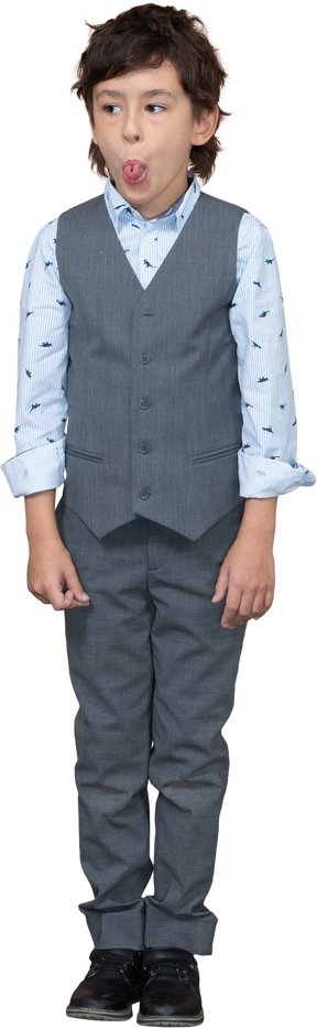 Front view of a cute boy in suit showing tongue