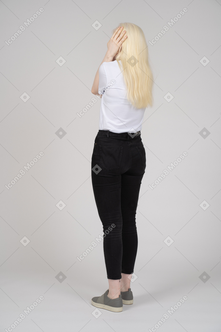 Vista traseira de uma mulher de cabelos compridos, segurando sua cabeça