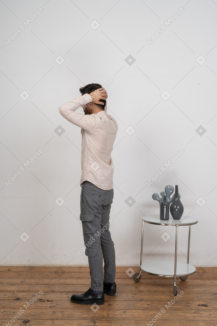 Vista lateral de um homem com roupas casuais, posando com as mãos atrás da cabeça
