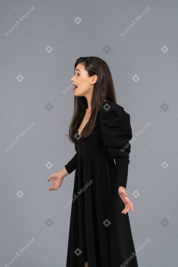 Vista laterale di una giovane donna che canta in un abito nero