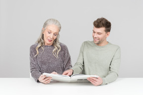 Elegante anciana y chico joven pasando por un libro juntos