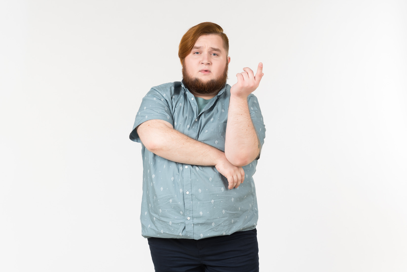 Pensive young overweight man standing with hands crossed
