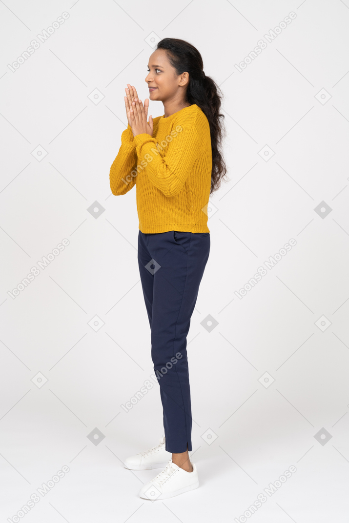 Vista lateral de uma garota feliz em roupas casuais esfregando as mãos