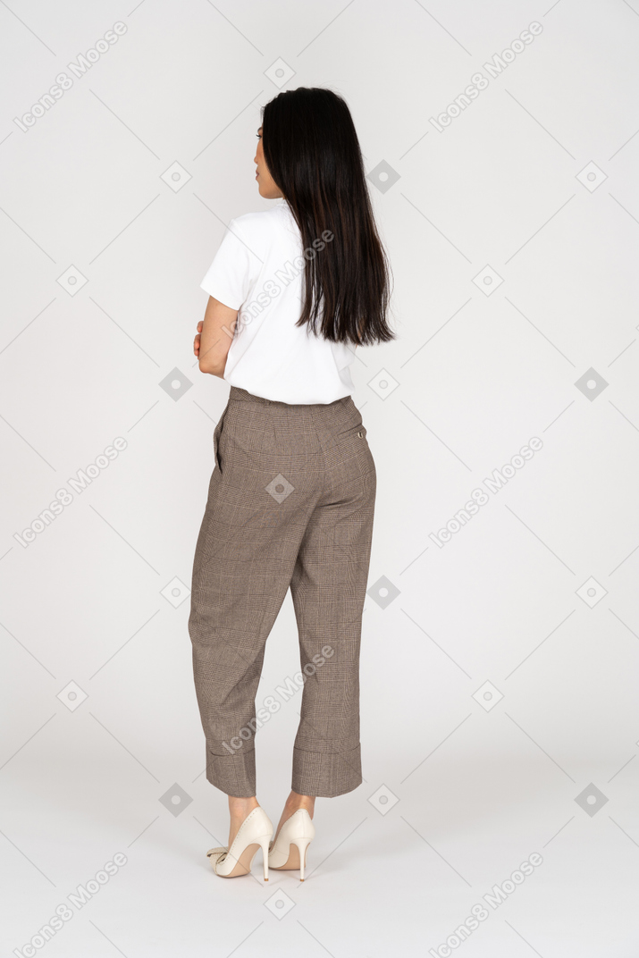 Back view view of a suspicious young lady in breeches and t-shirt crossing hands