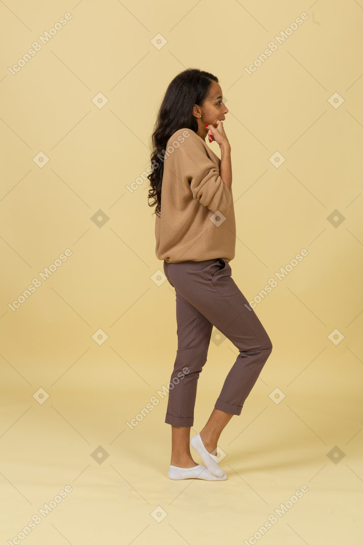 Side view of a funny dark-skinned young female putting finger in her mouth