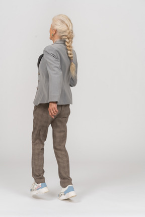 Rear view of an old lady in suit walking