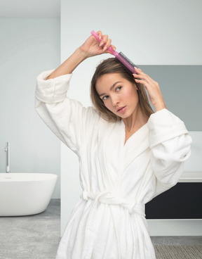 Jovem mulher pegando o cabelo com escova de cabelo redonda