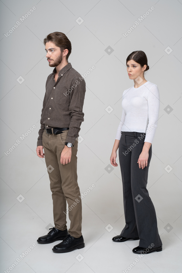 一对不高兴的年轻夫妇，在办公室服装中的四分之三的视图