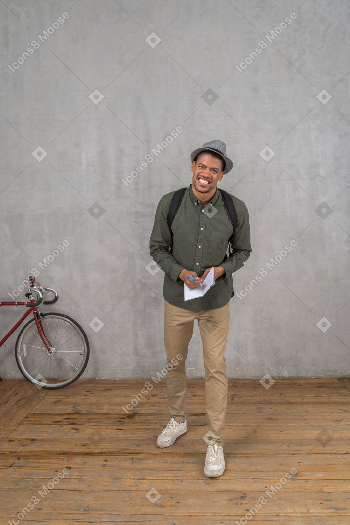 Homme prenant des notes dans un cahier et souriant