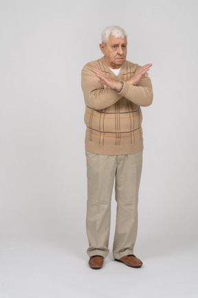 Front view of a sad old man in casual clothes showing stop gesture