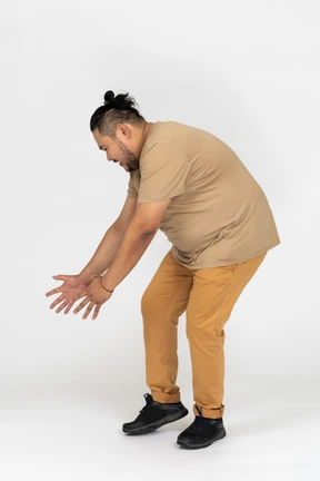 Hombre asiático sorprendido extendiendo los brazos hacia abajo y agachándose