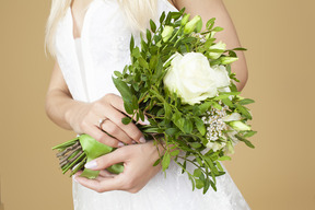 Sposa con un anello su una mano che tiene il bouquet da sposa