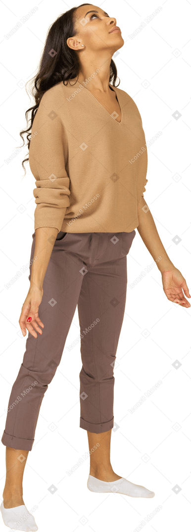 Vista di tre quarti di una giovane donna dalla pelle scura in piedi con le braccia aperte