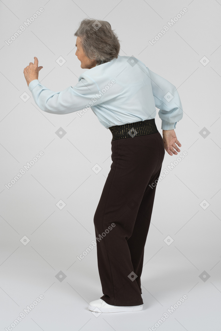 Three-quarter back view of old woman with raised hand
