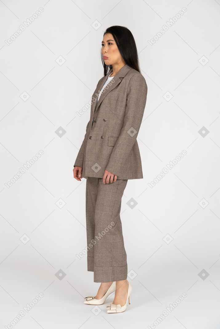 茶色のビジネススーツを着た不機嫌そうなふくれっ面の若い女性の4分の3のビュー