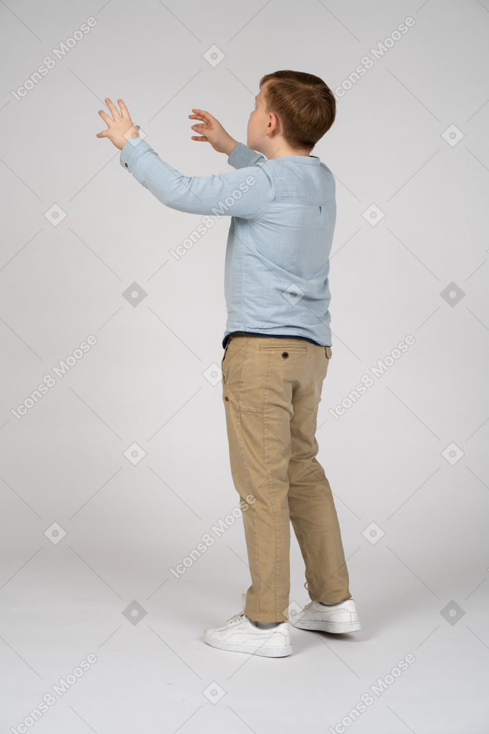 A young boy is standing with his arms outstretched