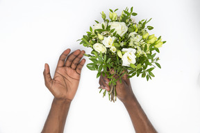 Mãos masculinas pretas segurando o buquê de flores