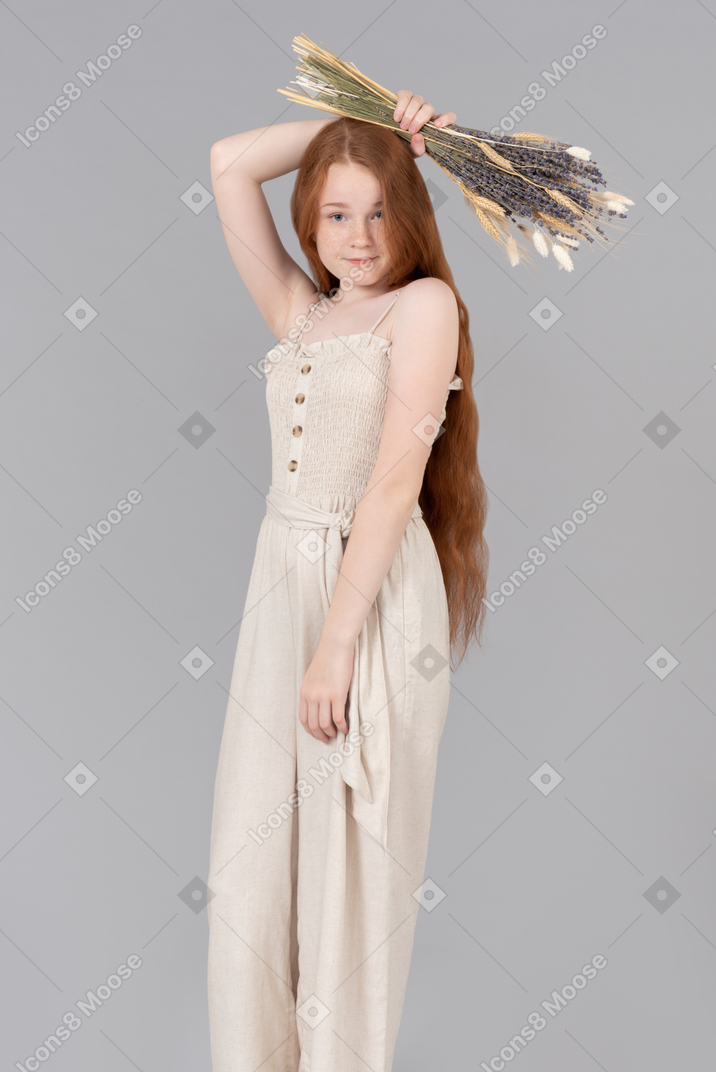 Teenage girl in beige overalls holding dried flowers