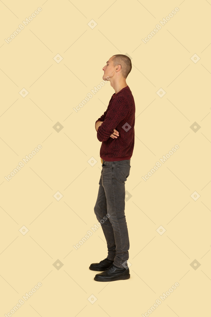 Side view of an offended young man dressed in casual clothes crossing his hands