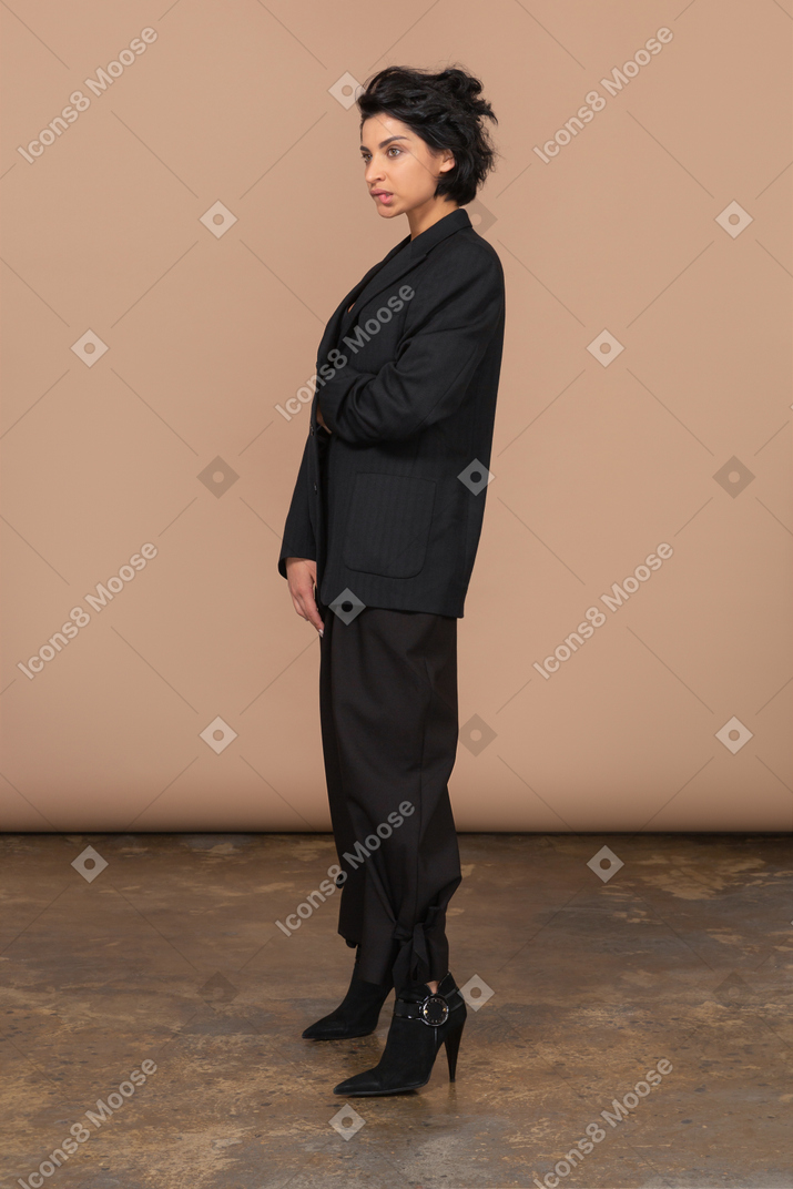 Three-quarter view of a thoughtful businesswoman in a black suit biting lips and looking aside
